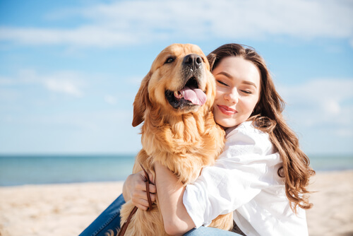 Mujer abrazando a su perro en la playa